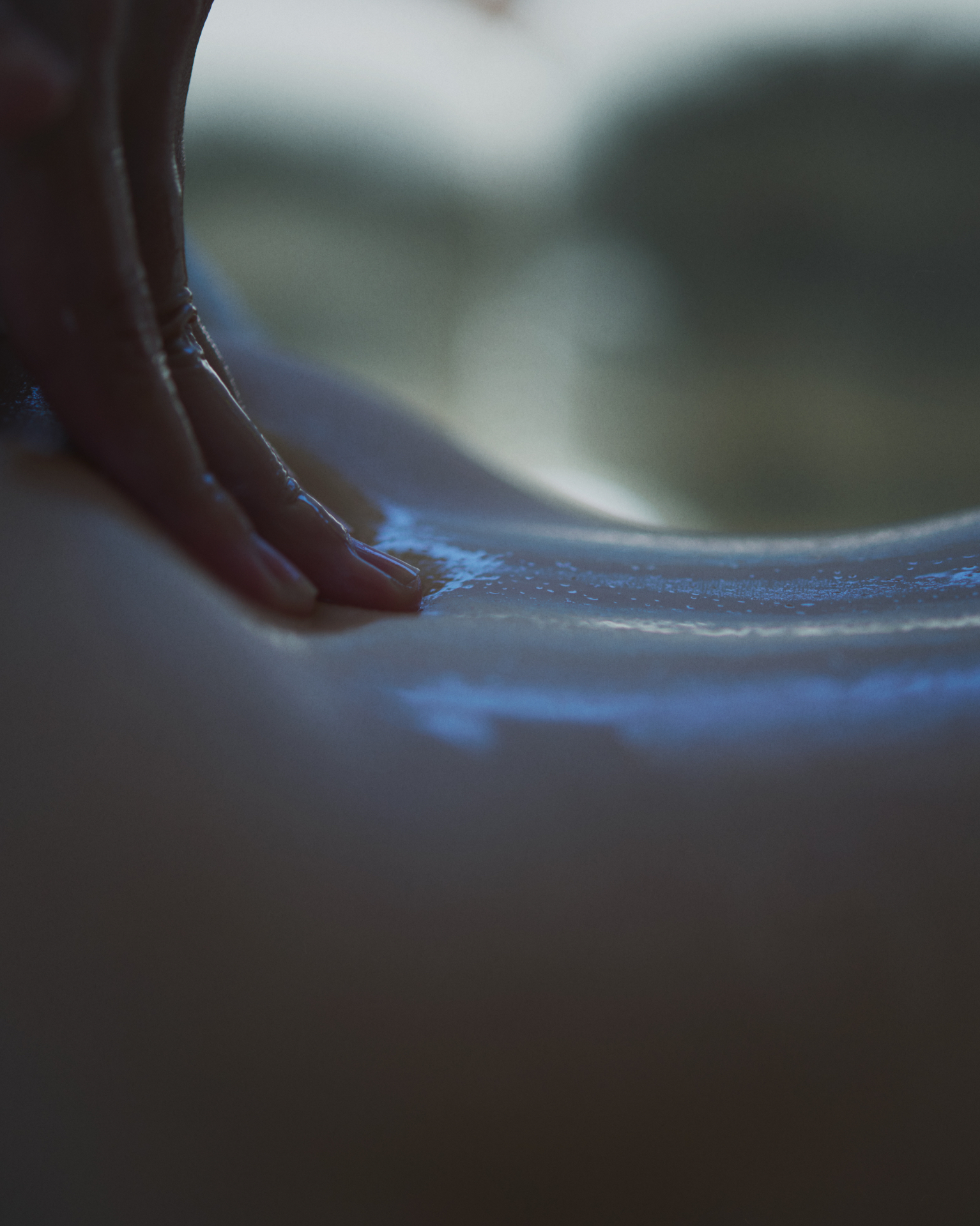 Hand touching water-lit surface in soft blue light